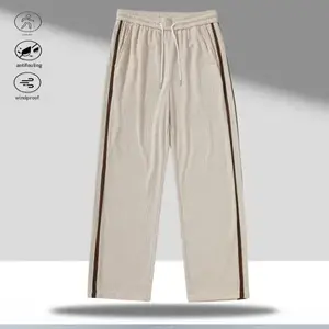 A pair of apricot colored corduroy straight leg casual pants with brown side stripes, featuring a retro casual style. The drawstring waistband allows for flexible adjustment to fit different waist sizes, making them easy to wear and comfortable. The class