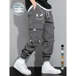 Men’s cargo pants with cartoon smiley face letter print and drawstring waist; casual regular fit functional jogger long pants; versatile men’s bottoms for all seasons; men’s casual pants.