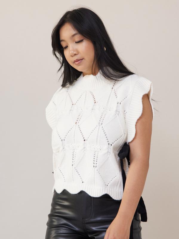 Wishlist Vest - White comfy cable knit sweater vest with scallop details, black side bows, and a turtleneck, offering a slightly oversized fit