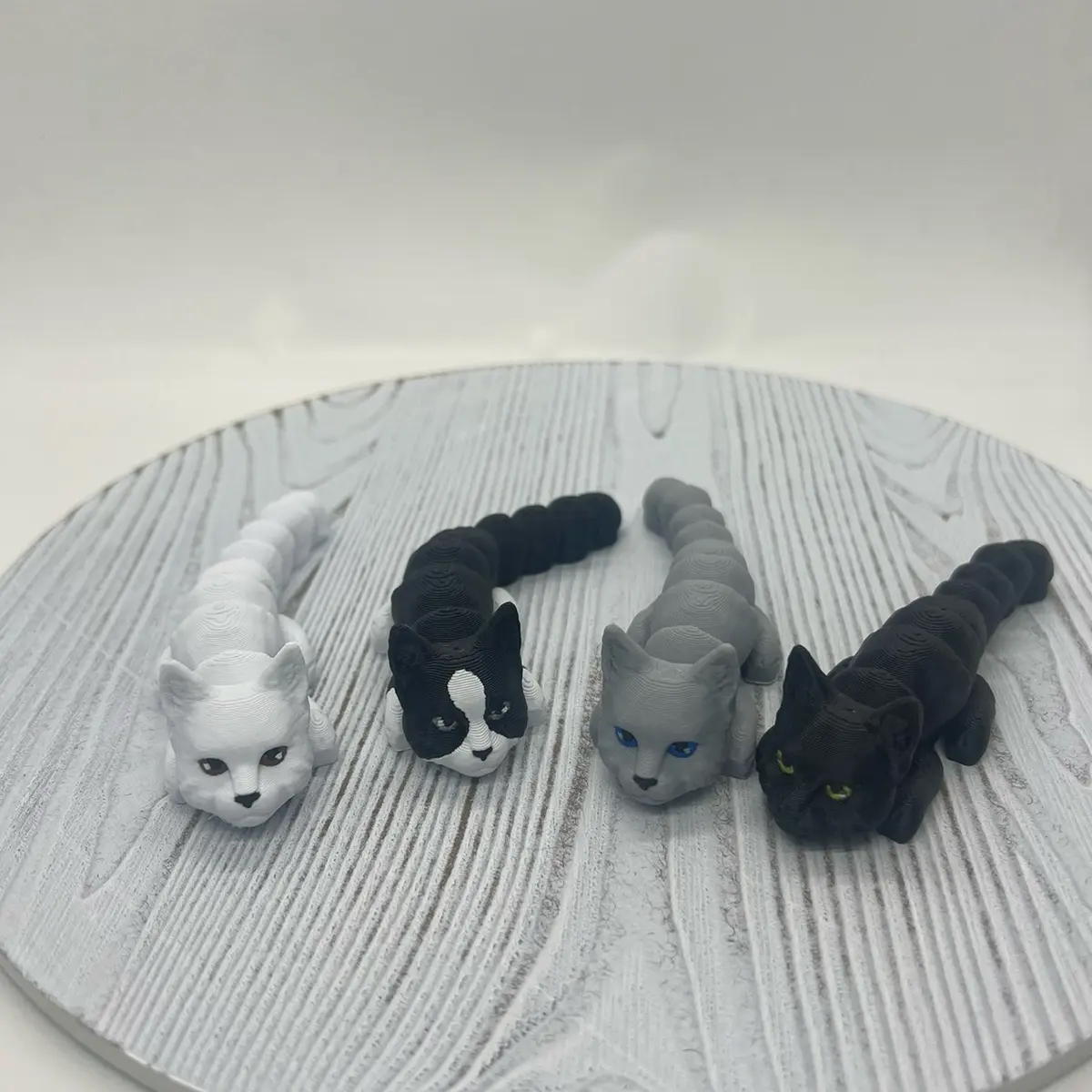 3D Printed Cats - Three Cat Figures in Assorted Colors Including White, Black & Gray on Gray Background