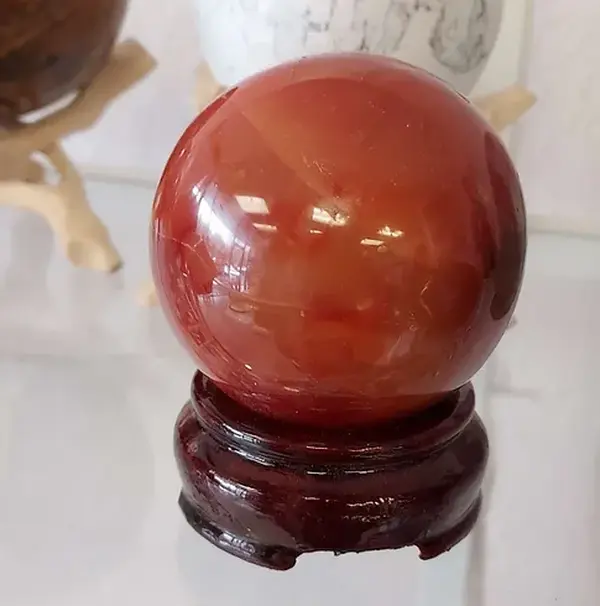 Carnelian Crystal Sphere - Elegant Design with Smooth Surface and Dark Base