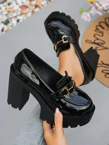 A pair of Women's Platform Block Heel Loafers, Patent Leather Upper, Chunky Lug Sole, Metal Buckle Accent, Gothic Inspired, Edgy Platform Shoes, High Heel Loafers for Parties, Night Out, Street Style, Bold Footwear, Slip-On Design, Trendy Heeled Loafers