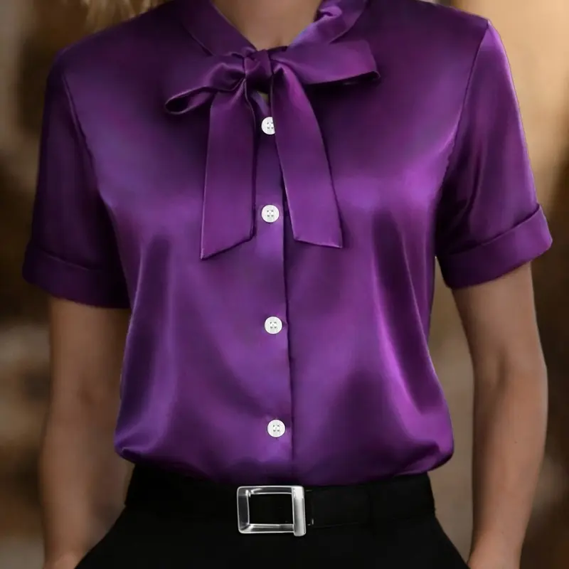 Classic short-sleeved satin shirt blouse with a ribbon detail at the neckline, fitted. Elegant solid color, perfect for spring and summer wear. A stylish women's top.