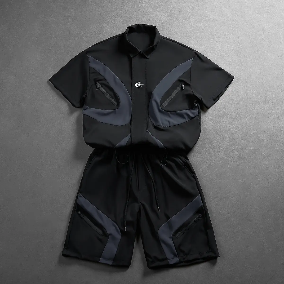 Men’s two-piece set featuring a black-and-gray color contrast: short-sleeve collared shirt and shorts. Streetwear casual outfit with symmetrical curved patchwork and layered design. Garment includes zippered pockets for convenient storage of small items.
