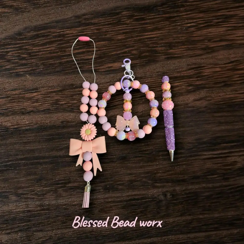 light pink and light purple 3 piece set. wristlet with a keychain attached, beaded pen, and car charm.