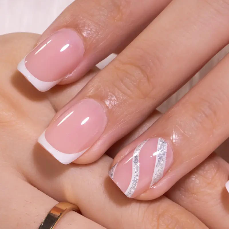 An elegant short square French manicure featuring soft nude pink nails with crisp white tips, paired with a delicate silver and white swirl accent design on the ring finger, creating a timeless and sophisticated look perfect for any occasion.