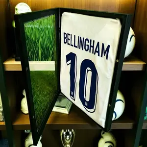 Black-framed sports jersey display case, 18x14 or 13x13 inch options, heavy-duty stand secures jerseys and sweatshirts, transparent scratch-resistant design protects collectibles, wall-mountable, ideal holiday gift for collectors, fan caves, and game room