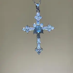 A cross necklace imbued with protective energy, featuring exquisitely set blue-white sapphires—blue gemstones—inspired by a designer’s original concept and conveying the Christian faith’s blessing of peace.