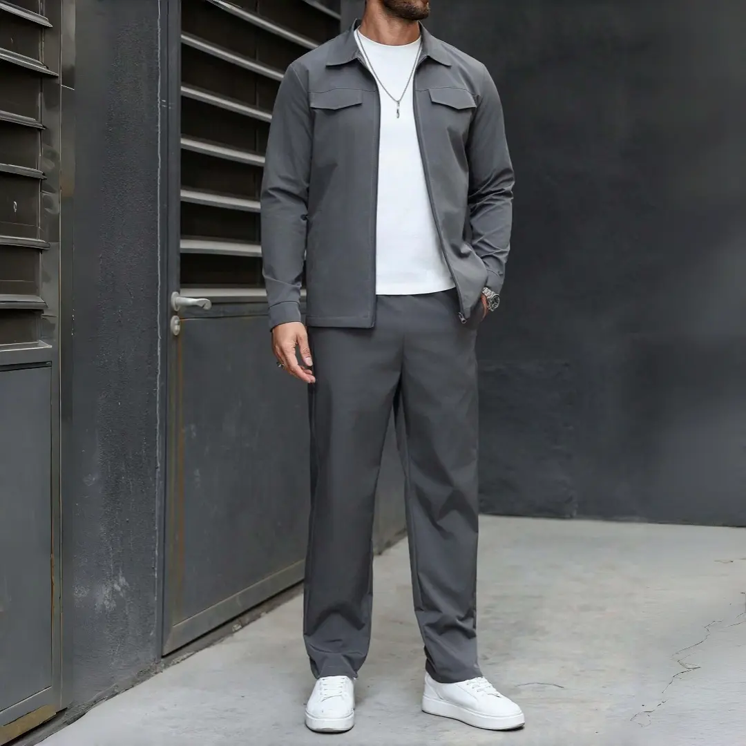 Men’s two-piece set in dark gray: a zip-up jacket with a notched lapel and straight-leg pants. A mature, minimalist casual outfit with neat stitching at all seams—the jacket cuffs are neatly tapered, and the pants have straight legs that resist deformatio