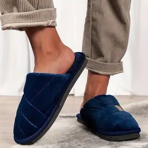 Men’s plush slide slippers with quilted velvet/soft fabric, fuzzy-lined interior, and a branded patch—non-slip soles for cozy, stylish indoor lounging.