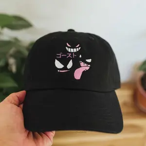 Black embroidered dad hat featuring a playful cartoon-style face with pink details and Japanese text. Made from soft cotton with a curved brim, perfect for adding a fun and trendy touch to your casual outfits.