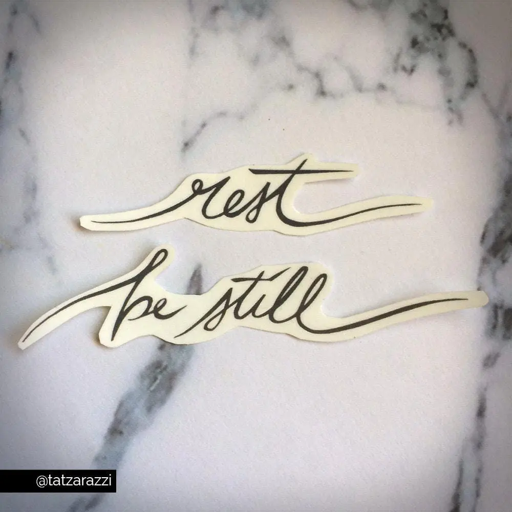 Rest be still temporary tattoo script calligraphy cursive flowing text black simple minimalist peace calm encouragement scripture church