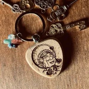 Granny’s Love Charm Keychain. Wood engraved with a portrait of Granny Goblin herself, with 5 tiny rocks selected from her personal collection.
