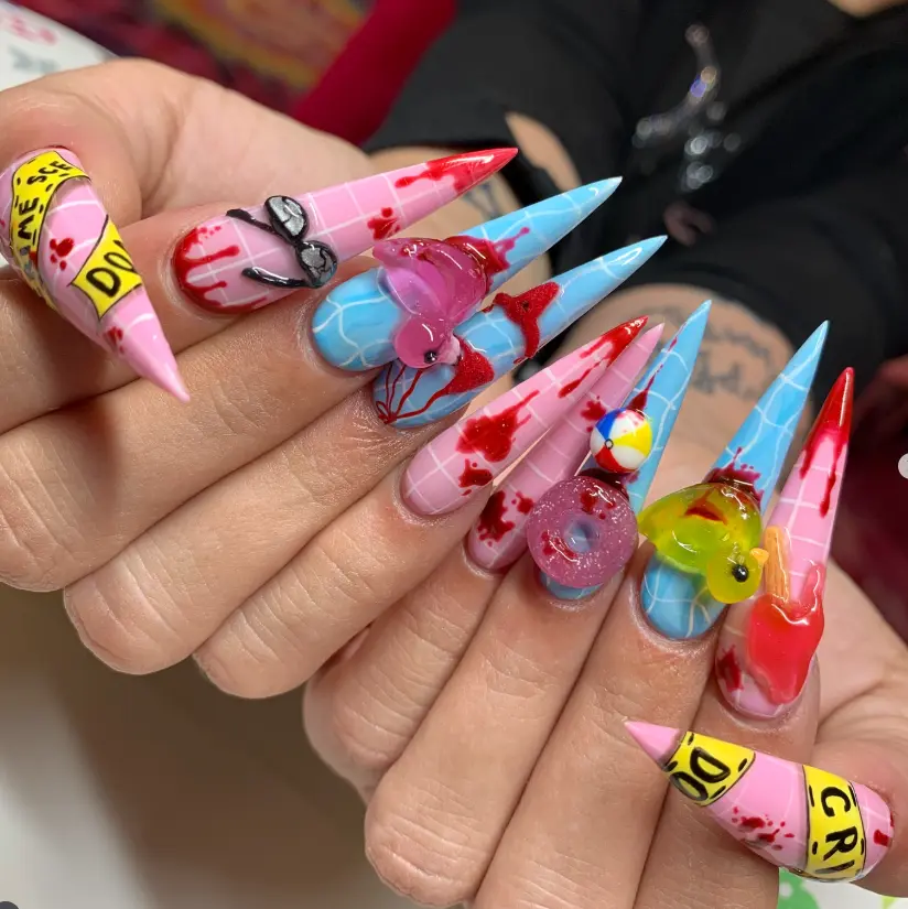 summer horror stiletto nails with 3d duck, donut, popsicle, bikini and glasses on pink blue grid tips splattered in red for a creepy pool party vibe