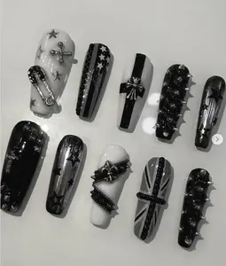 Edgy black and white punk nails with stars, crosses, spikes, chains, and Union Jack accents—perfect for a rebellious rock-inspired statement look