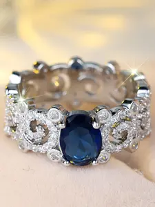 A stylish, high-end egg-shaped blue sapphire ring with intricate, openwork patterns and subtle white diamond inlays, perfect for a sophisticated, minimalist, and cool-toned feminine look.