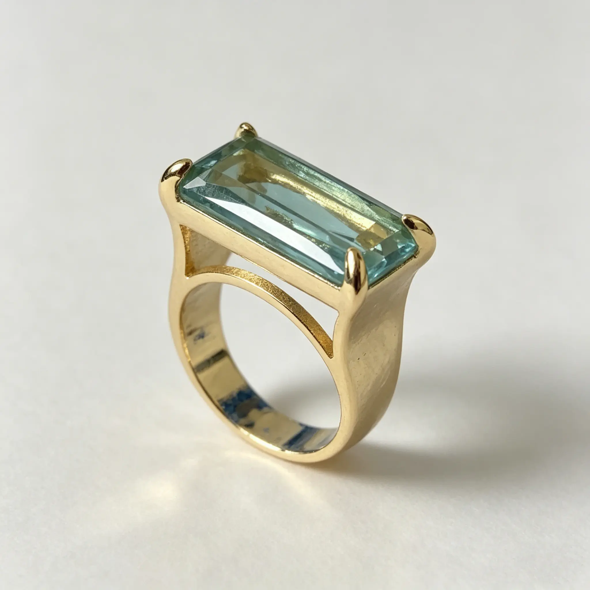 This wide, openwork ring in a vintage-inspired, affordable luxury style is crafted from gold-plated copper and set with a rectangular-cut light aqua synthetic zirconia, making it an affordable luxury accessory that combines stylish design with great value