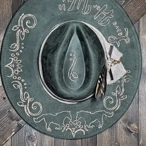 Introducing our "Leave Her Wild" olive green suede fedora cowboy hat thats is burned and hand painted in rose gold with rhinestones, burlap, feathers, and genuine leather hatband. Embellished with a cowskull