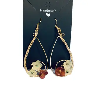 Wire wrap earrings with burgundy and pale yellow flowers worked into the earring design .