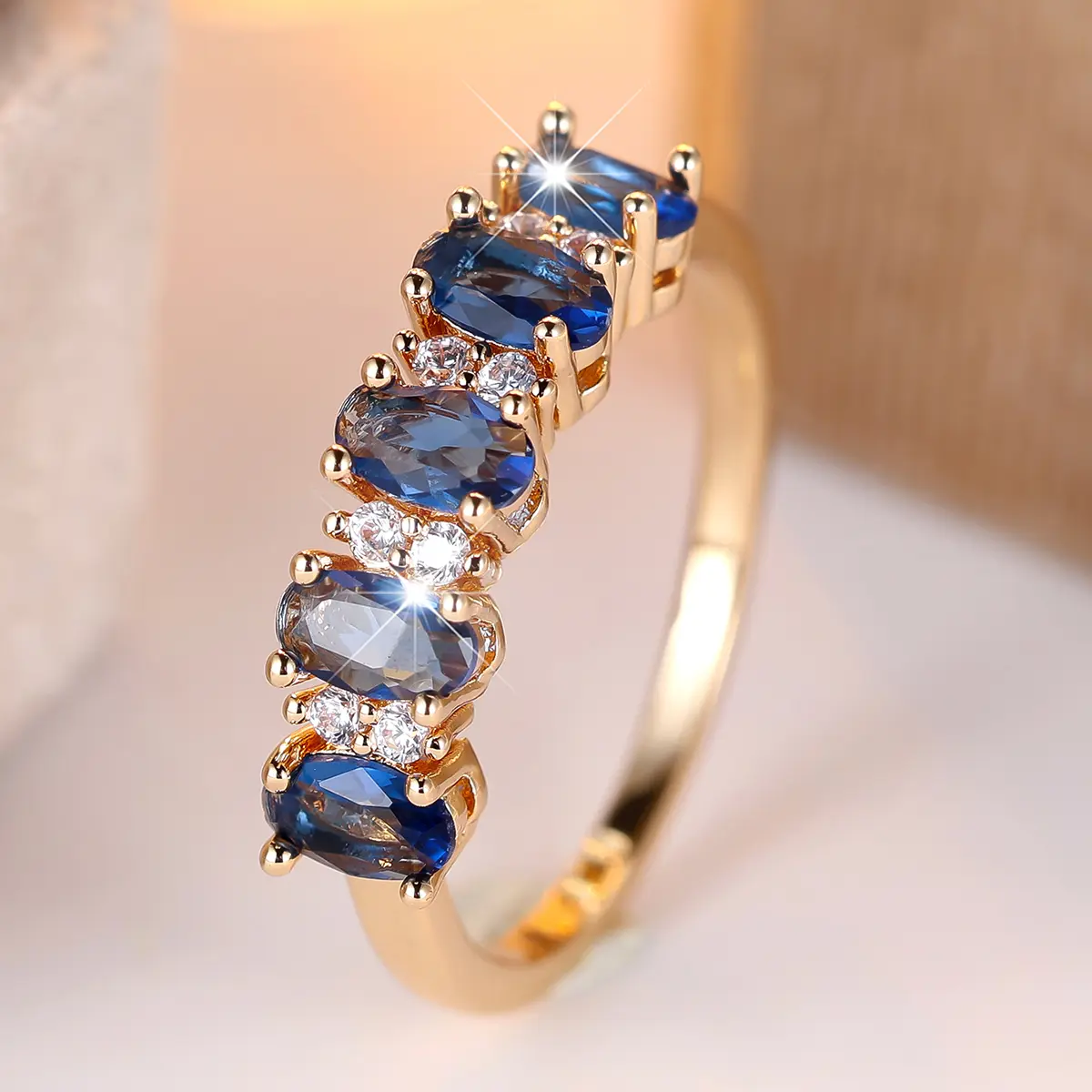 A gold egg-shaped ring with a sapphire blue edge and white diamonds, made of synthetic blue zirconia, is suitable for women to wear daily at wedding parties