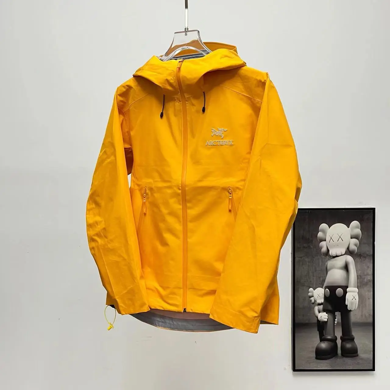 Bright yellow hooded outdoor shell jacket waterproof windproof fabric full zip closure multiple zipper pockets for hiking camping and daily outdoor trips