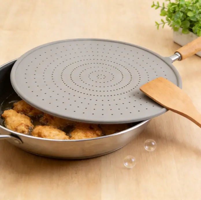 Round kitchen oil splash guard made of soft food-grade silicone, uniform circular vent holes and lightweight wood grip, ideal to avoid messy grease splatters during deep frying and stir-frying