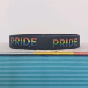 LGBTQIA+ PRIDE Silicone Wristband showing "PRIDE" all around the band. Rainbow letters over a black band. Our original and discontinued line, adopt yours today before it's sold out. = )
