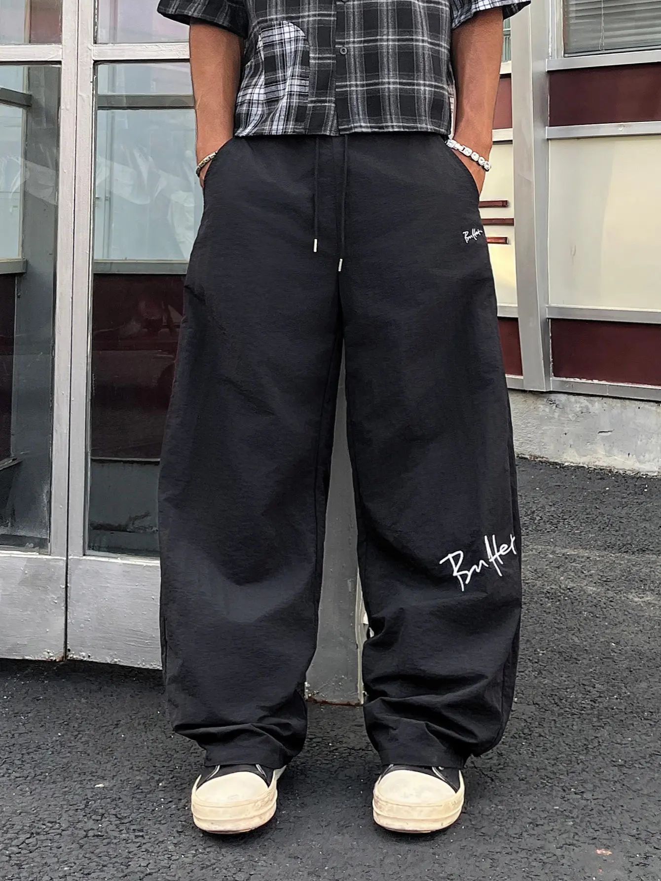 Unisex black parachute pants with handwritten letter embroidery, drawstring, wide legs – crinkled quick-dry fabric, adjustable elastic waistband, side pockets, relaxed drapey fit, American high street style for daily commutes and city walks