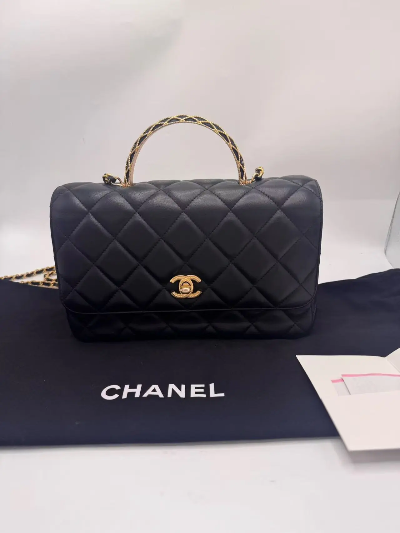 Pre-owned CHANEL vintage style black & gold CF with metal top handle (2023). Features a distinctive embossed logo design. Base length 24 cm. 98% new
