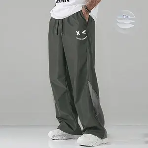 Men’s black athletic pants with white side stripes and smiley print design; casual sportswear; loose jogger pants; stylish street fashion joggers; drawstring waist; straight cut; polyester men’s pants.