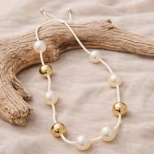 Adjustable ivory cord necklace with pearl effect beads and gold accents elegant boho chic statement necklace lightweight versatile summer jewelry Ibiza style adjustable length handcrafted feel soft neutral tones perfect for beach outfits resort wear casua