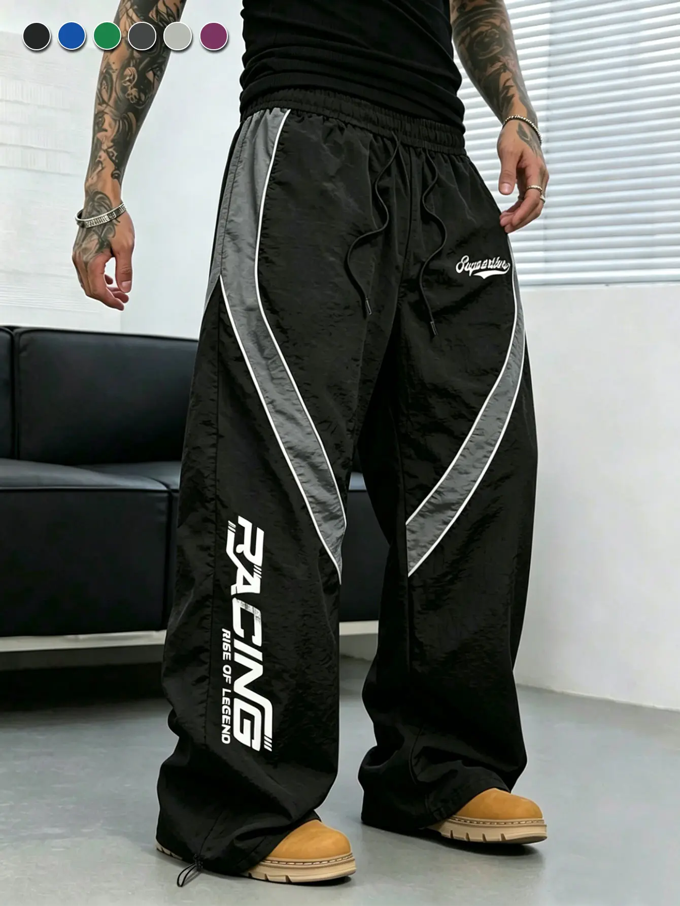Men’s black-and-gray racer pants with diagonal color blocking and a drawstring waist; vertical letter print, loose wide-leg streetwear long pants for men.