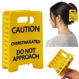 Yellow logo with black text warning of excessive stimulation, unique design statement suitable for funny hair clips for women and employees