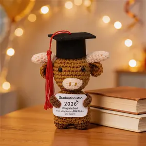A handmade, crocheted Highland cow plushie wearing a graduation cap—the perfect small gift for graduation season or a charming desk ornament.