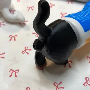 Cat Cap Guard for toothpaste - Shows a White Cat-shaped Object Next to a Tube, Details Unknown