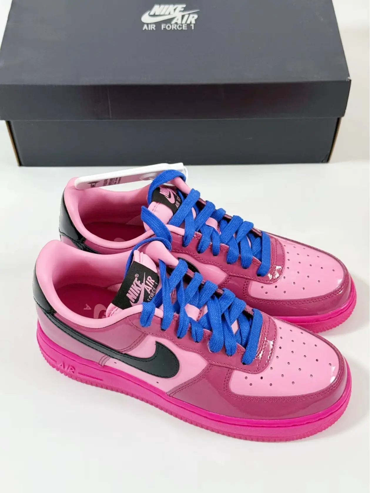Patent leather low‑top skate sneakers pink magenta contrast tone, bright blue laces flat rubber outsole lace‑up street casual footwear