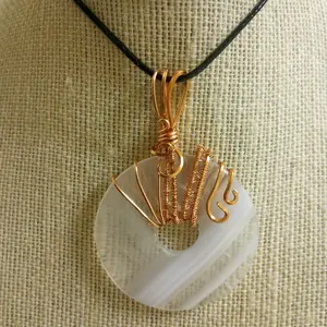 Lined white agate in donut cut polished pendant, wrapped in copper