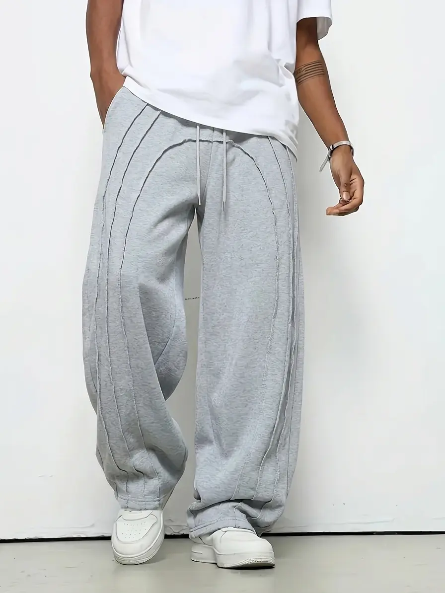 Men’s high-street deconstructed jogger sweatpants with curved split design and raw hem; contrast stitching and 3D line patchwork; elastic drawstring waist; drapey floor-length athletic pants; niche vibe gray straight-leg casual joggers. backtoschool