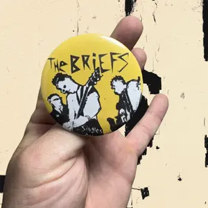 The Briefs Punk Pin Large 2.25” Button - Yellow with Black and White Design