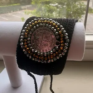 Medalla grande en manilla tejida color negro.