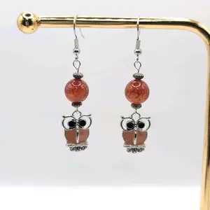 These earrings showcase adorable owl dangles in light brown and silver hues, complemented by a beautiful bead suspended above the owls for an elegant and charming look. Actual measurements are just under 2 1/4" long and 1/2" wide.