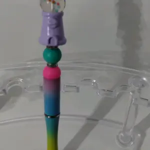 A green blue and purple plastic ink pen with a bubble gum machine focal bead. Accented with pink and kelly green food grade silicone beads. Black ink.