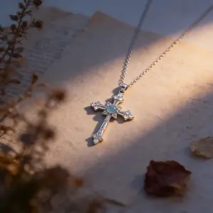 A cross necklace imbued with protective energy, featuring exquisitely set blue-white sapphires—blue gemstones—inspired by a designer’s original concept and conveying the Christian faith’s blessing of peace.