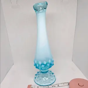 Vintage Fenton Bud Vase in Opalescent Blue Hobnail design is a stunning addition to any collection of art studio glass. Measuring approximately 7.5 inches, this vase features a beautiful blue hue that reflects light in an iridescent manner