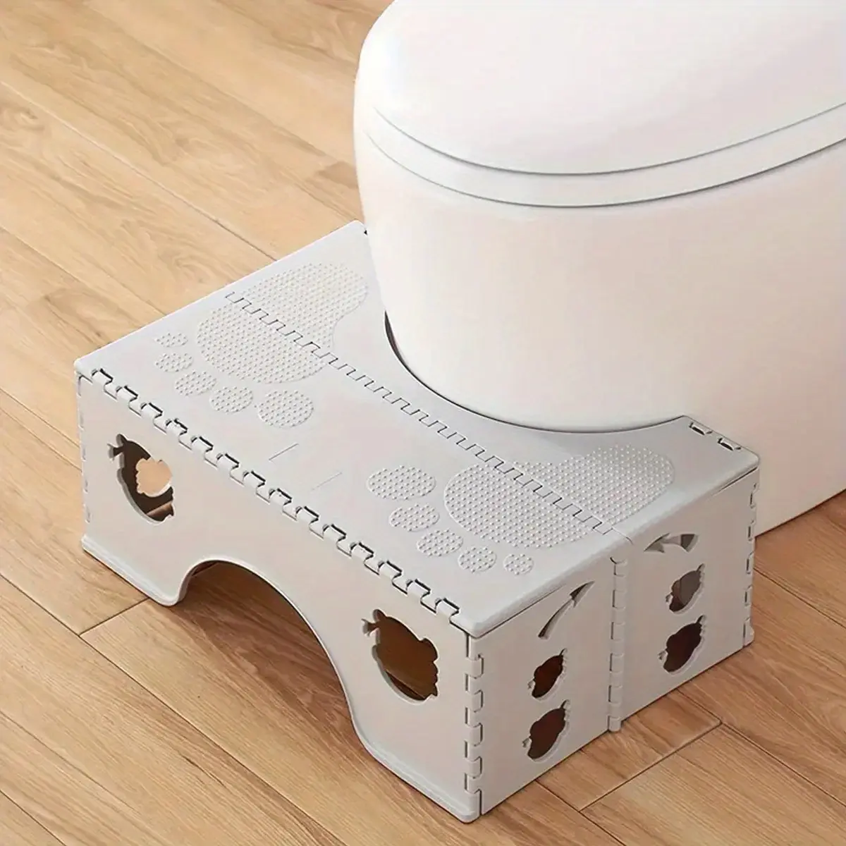 A plastic folding toilet stool - a small cubicle design that saves space, a non-slip bathroom step to help with proper posture, and easy to fold for storage and travel.
