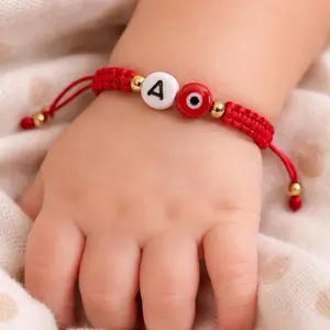Adjustable red bracelet with evil eye and initials.