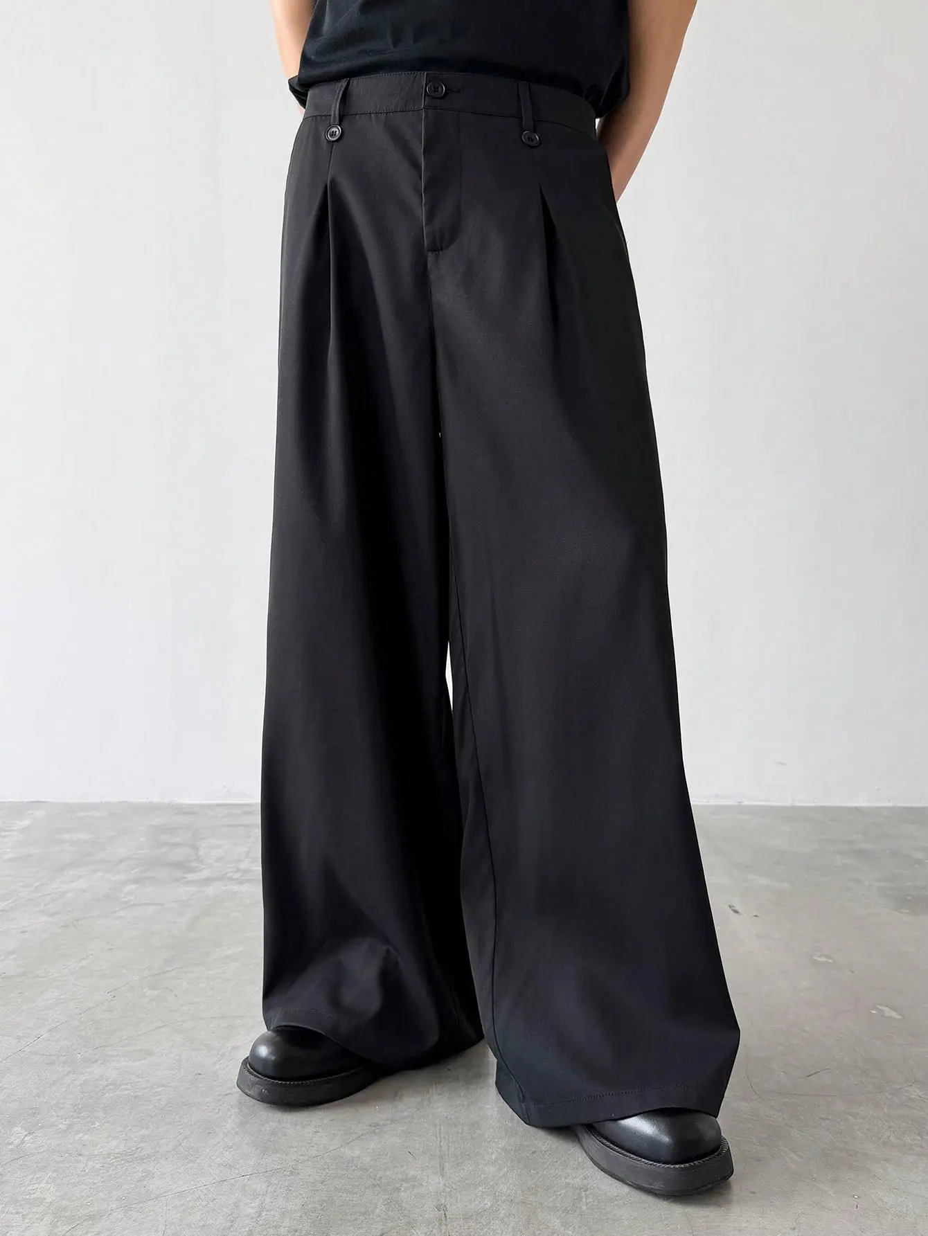 One black high waisted pleated wide leg men’s dress pants, urban casual style; double button waist with front pleats; drapey fabric that shapes the legs; suitable for men’s everyday commuting, shopping, and exploring stores; relaxed, versatile, stylish, a