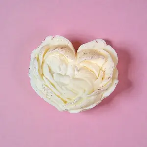 A soy candle in the shape of a flower holding a baby inside it.