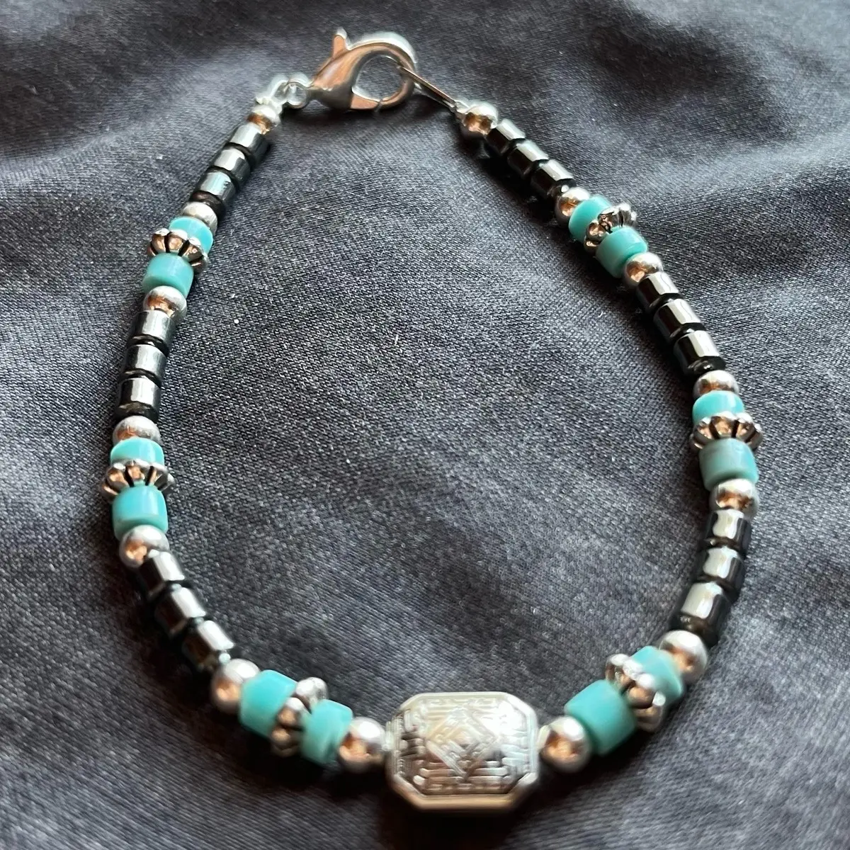Navajo handmade anklet made with hematite stones and sleeping beauty turquoise heishi beads with a square basket design center peice.