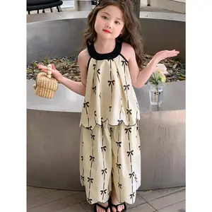 A Two-Piece Outfit for Girls Featuring a Sleeveless Vest with a Bow Print And Irregular Hem, Paired with Matching Trousers. This New Girls' Is Versatile And Embodies a Casual, Fashionable Style with a Knitted Design, for Outdoor
